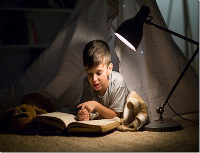 Little boy secretly reading book